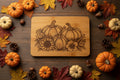A rectangular bamboo cutting board with rounded corners, featuring a detailed laser-engraved design of three pumpkins, sunflowers, and autumn leaves. The board is shown resting on a wooden surface against a plain light gray wall.